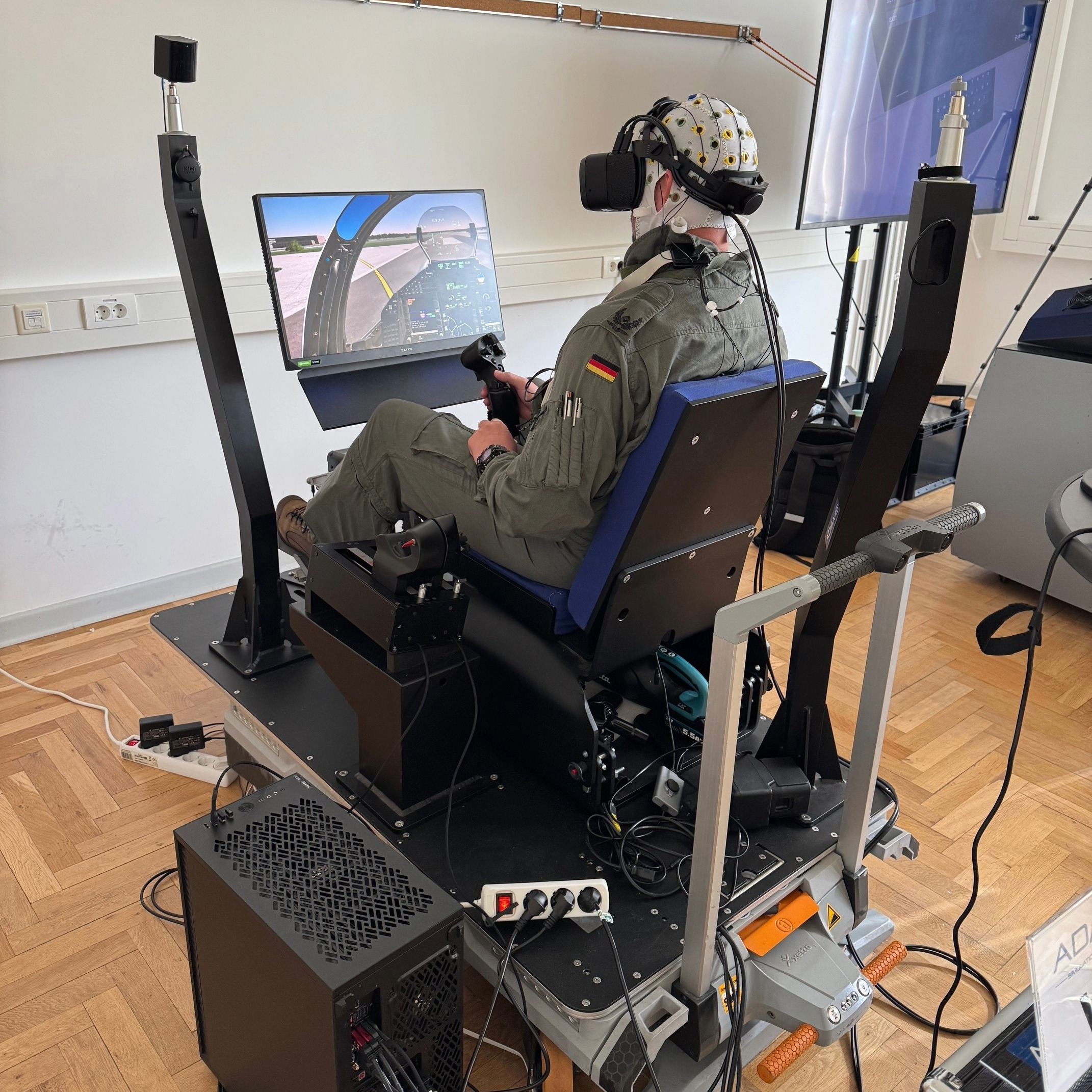 This image shows the Virtual Reality condition. A jet pilot inside of a simulator seat, wearing a VR headset
